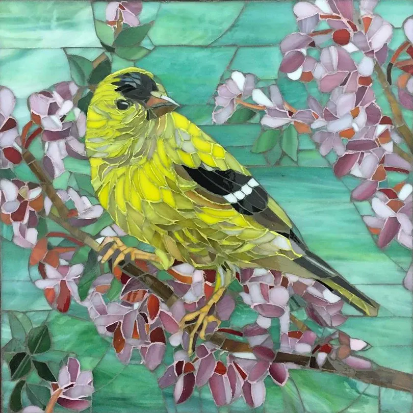 Glass mosaic of a yellow goldfinch on a blossom branch